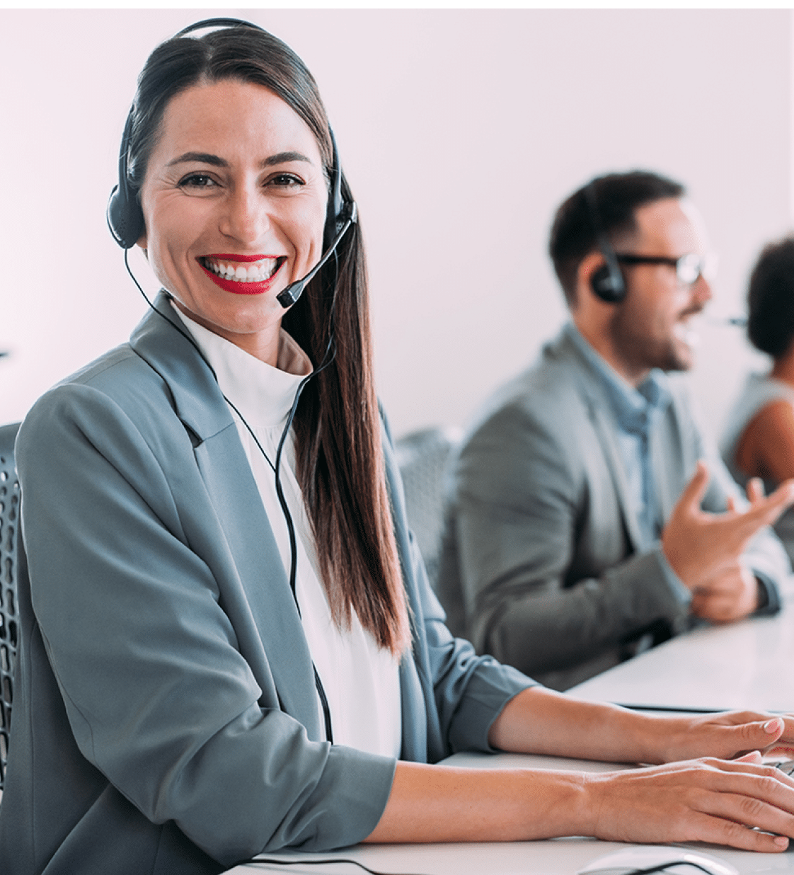 Shot of call center operators working in the office. Female call center agent working with her colleagues in modern office. Smiling beautiful businesswoman working in call center.