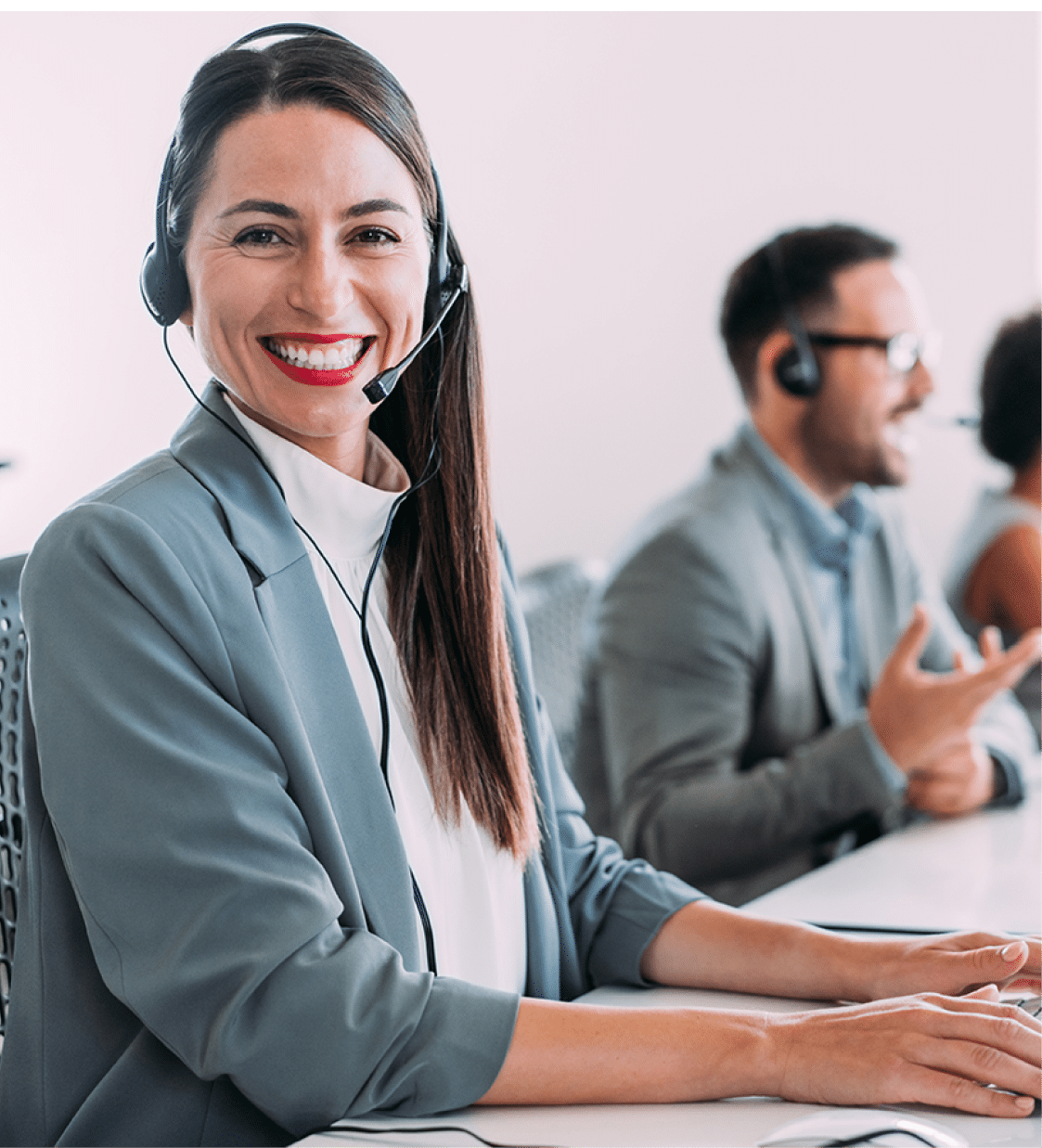 Shot of call center operators working in the office. Female call center agent working with her colleagues in modern office. Smiling beautiful businesswoman working in call center.