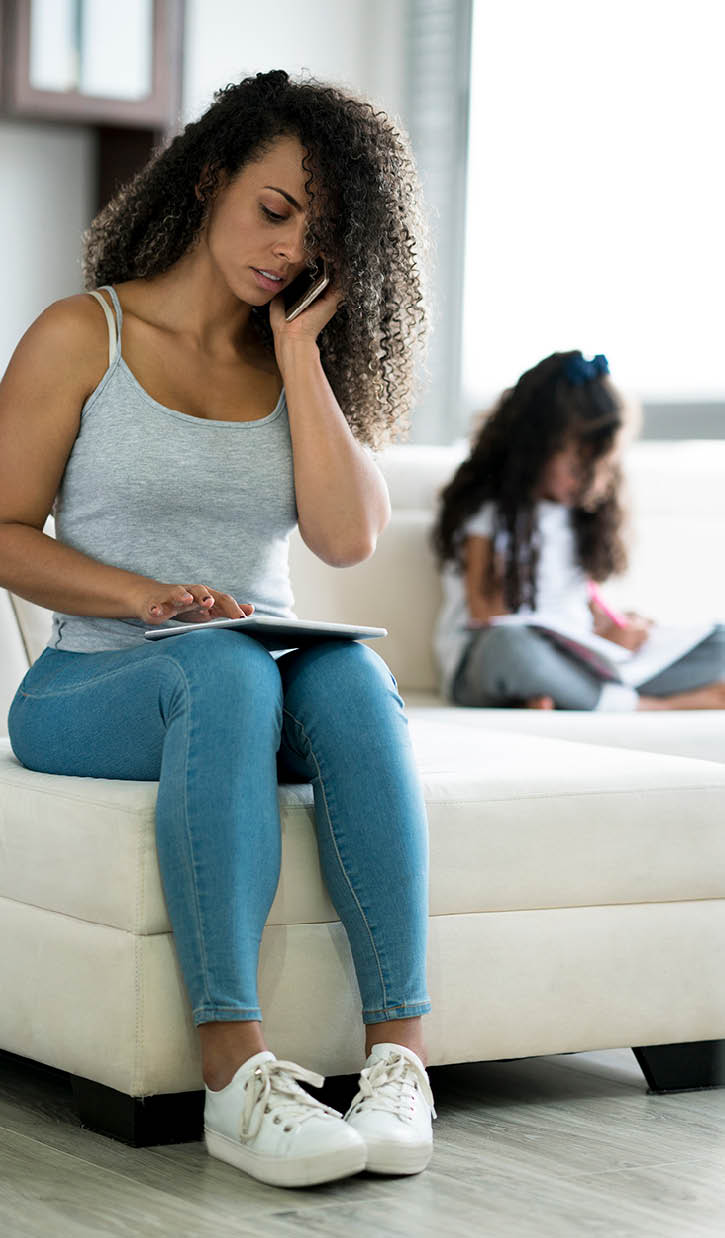 Latin woman between 25 and 35 years old is a mother working serious next to her daughter from home