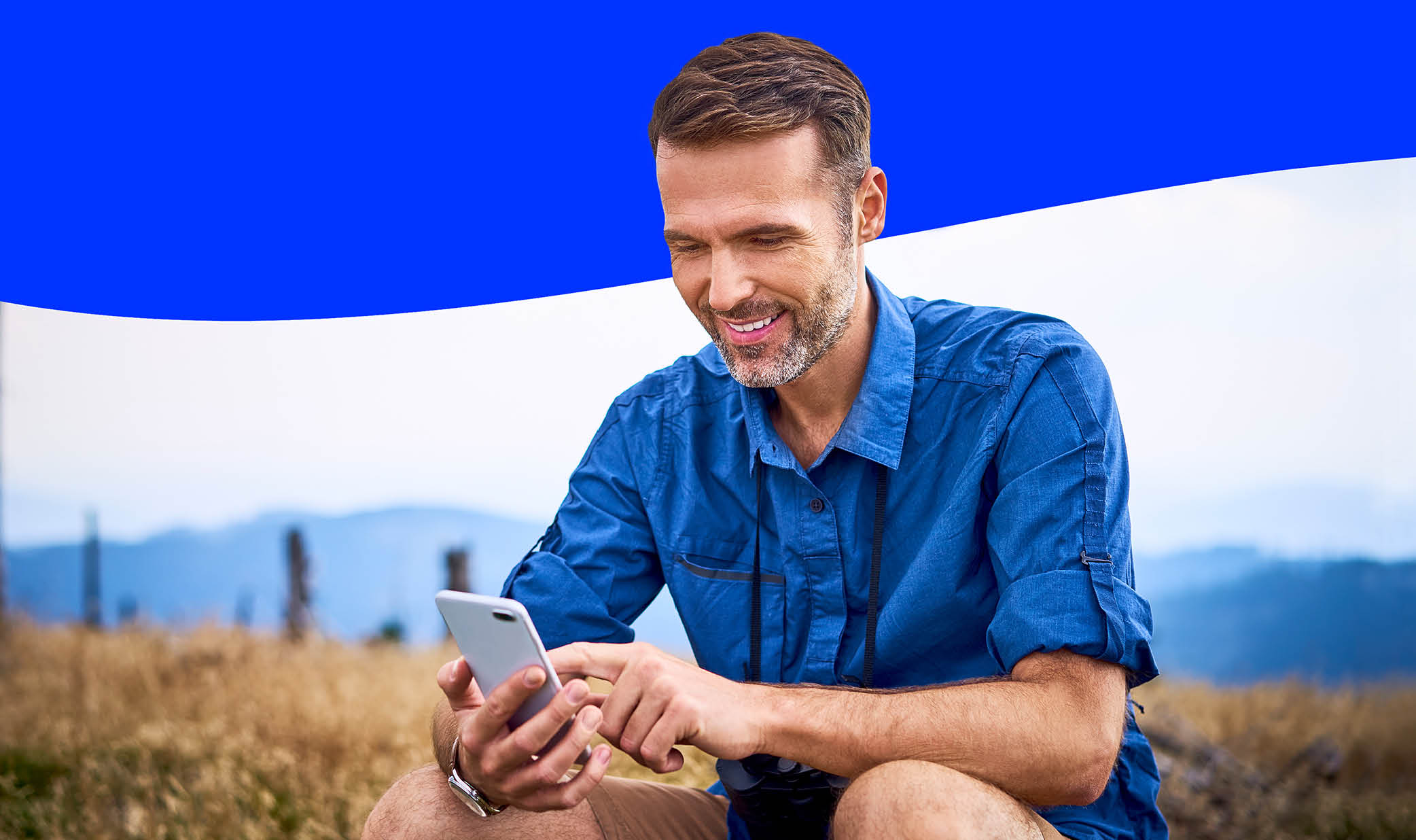 Side View Of African American Guy Using Smartphone Browsing Internet Sitting On Couch At Home. Black Man Texting On Cellphone Or Using New Application On Mobile Phone Indoors