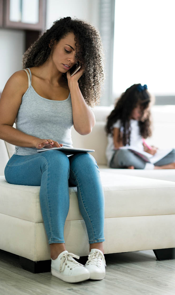 Latin woman between 25 and 35 years old is a mother working serious next to her daughter from home